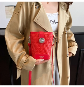 Detail of red woven texture crossbody bag with silver metal twist lock on beige coat