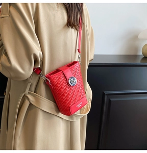 Detail of red woven texture shoulder bag with silver clasp on beige trench coat