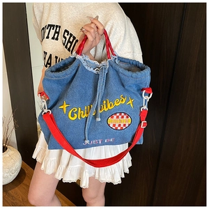 Detail of blue denim tote bag with Chill Vibes embroidery and red strap accents