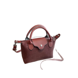 Deep red dumpling handbag in matte and smooth leather with shoulder strap on white backdrop