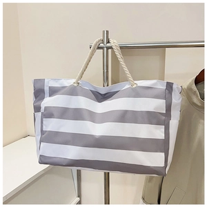 Detail van gestreepte canvas tas met dikke witte touwhandvatten en metalen oogjes