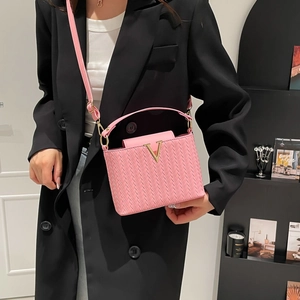 Pink woven leather shoulder bag featuring a gold V-buckle with adjustable strap