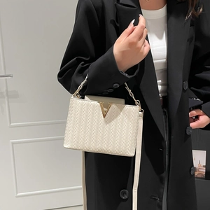 Detail of white woven texture handbag with golden V-shaped metal buckle and slim strap