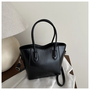 Detail der schwarzen Ledertasche mit FASHION-Gravur und goldenen Metallelementen