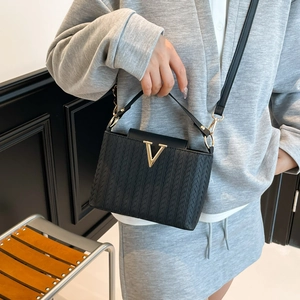 Detailed view of woven black leather tote with gold V hardware worn by a model