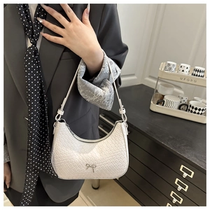 Detail of white woven texture crescent bag with a decorative silver metal bow