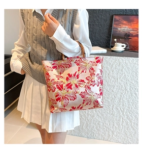 Detail of embroidered tote bag featuring traditional floral patterns and bamboo handle
