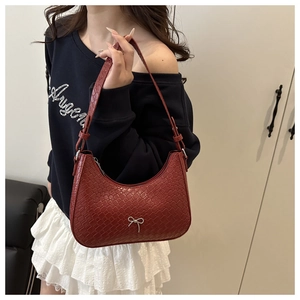 Detail of burgundy woven texture shoulder bag with small silver bow and metal zipper