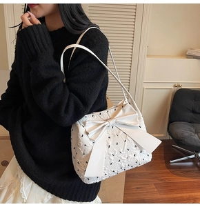 Détail d'un sac cabas blanc texturé avec un grand nœud porté par un mannequin