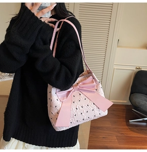 Détail du sac seau rose matelassé avec grand nœud en satin et motif lapin porté