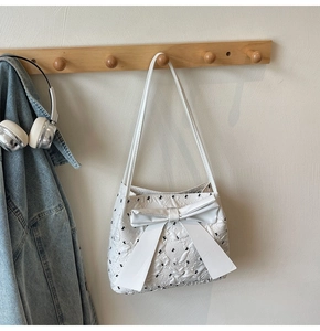 Détail du sac à bandoulière blanc avec nœuds noirs et texture de tissu gaufré