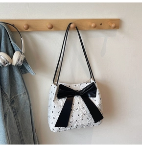 Détail du sac seau matelassé blanc avec nœud noir et fines bretelles d'épaule