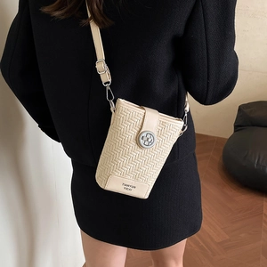 Beige woven leather crossbody bucket bag with silver buckle worn by a model