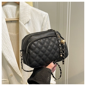 Detail of black quilted leather crossbody bag with gold chain and adjustment ball