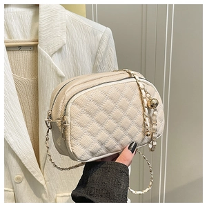 Detail of cream quilted crossbody bag with double zippers and gold chain strap