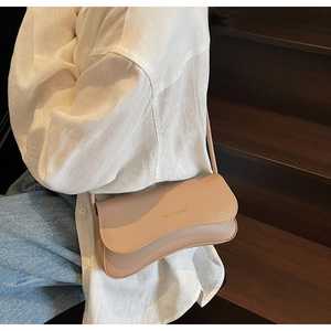 Gros plan d'un sac sous les bras beige minimaliste avec logo doré sur bois