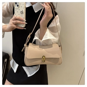Detail of elegant apricot patent leather shoulder bag with a gold oval metal lock