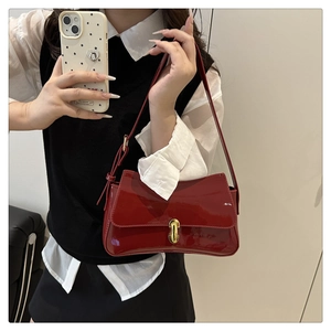 Close-up of wine red patent leather handbag with shiny finish and gold metal clasp lock