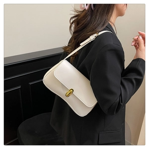 Close-up of a white minimalist shoulder bag with a polished golden twist lock clasp