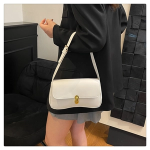 Side view of a white leather underarm bag with a golden cylindrical metal lock clasp
