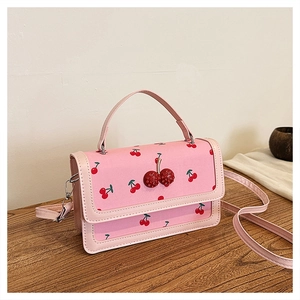 Detailed view of pink crossbody bag with cherry prints and 3D glitter cherry accents