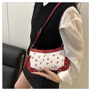 Close-up of cherry print handbag with red leather straps and silver metal rivets