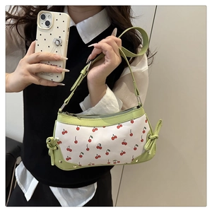 Detail of light green leather shoulder bag with white cherry print and decorative bows