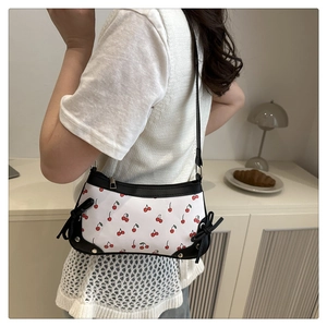 Detail of cherry print shoulder bag with black leather trim and decorative bows