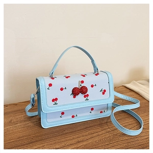 Detail of light blue crossbody bag with cherry prints and rhinestone buckle accent