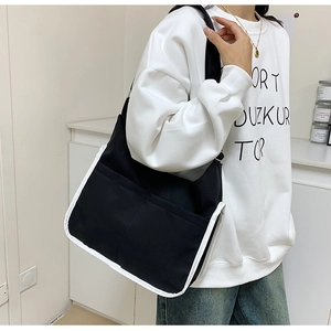 Detail of minimalist black and white canvas tote bag worn on shoulder by a model