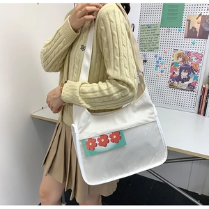 Détail d'un sac messager en toile beige porté par un mannequin dans un bureau douillet