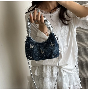 Détail du sac en jean avec papillons métalliques argentés et poignée plissée élégante