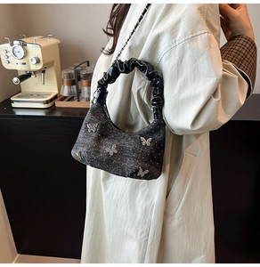 Détail du sac en denim avec papillons argentés en 3D et poignée à effet froncé chic