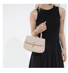 Detail of beige saddle bag with woven texture lid and golden horseshoe-shaped buckle
