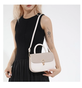 Detail of cream saddle bag with woven texture lid and golden horseshoe metal buckle