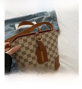 Detail of retro bucket bag featuring brown leather trim and canvas monogram pattern