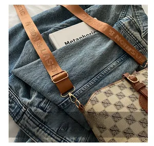 Detail of adjustable wide strap with fashion text on a vintage monogram bucket bag