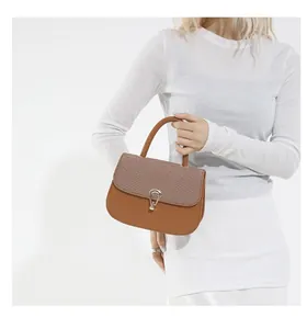 Close-up of caramel leather and textured fabric saddle bag with golden teardrop buckle