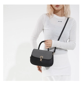 Model view of black and grey saddle bag with golden horseshoe buckle and strap