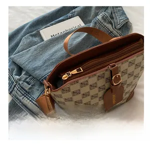 Detail of vintage bucket bag with monogram pattern and smooth golden zipper closure