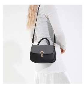 Detail of elegant black and grey crossbody bag with gold buckle on white outfit