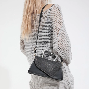 Sac à main noir chic avec paillettes argentées et poignée cœur sur mannequin femme