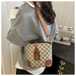 Detail of retro bucket bag with monogram pattern and wide brown woven shoulder strap