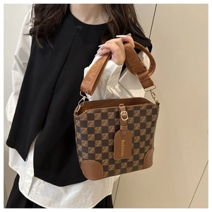 Close-up of retro brown checkered bucket bag with wide jacquard shoulder strap
