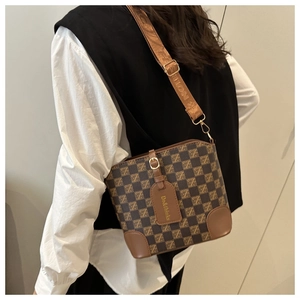 Detail view of checkerboard bucket bag with wide webbing shoulder strap on a model