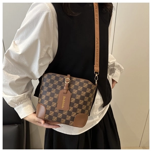 Detailed view of the brown monogram bucket bag featuring a wide woven shoulder strap