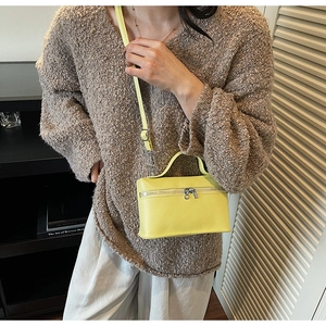 Detail of a bright yellow pebbled leather mini box bag with silver zippers and top handle