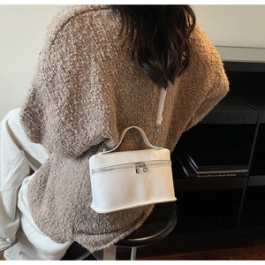 Detailed view of white pebble leather texture and silver buckles on a chic shoulder bag