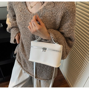 Close-up of white lychee pattern leather handbag with silver rings and dual zip closure