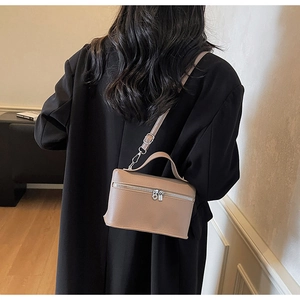 Rear view of a camel leather vanity box bag styled as a crossbody on a black coat